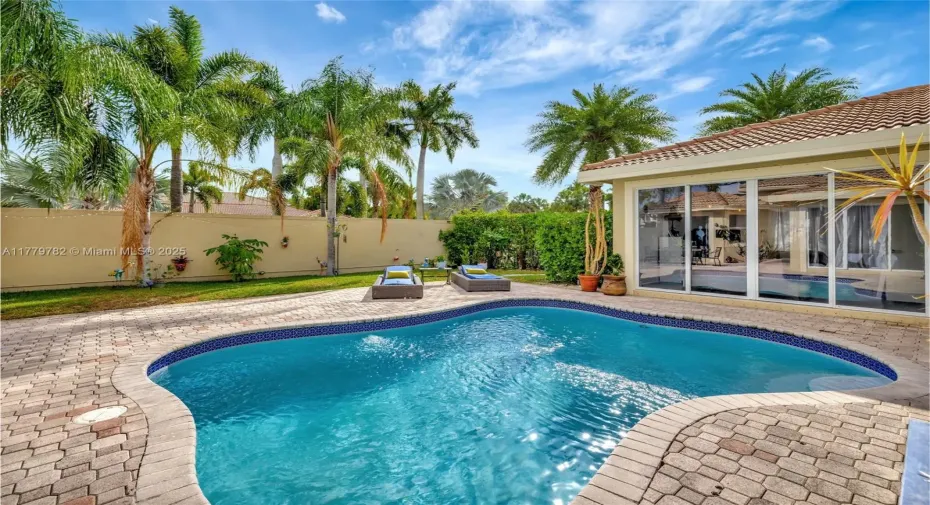 Tranquil tropical courtyard features a concrete in-ground pool and fenced patio, perfect for private outdoor relaxation.