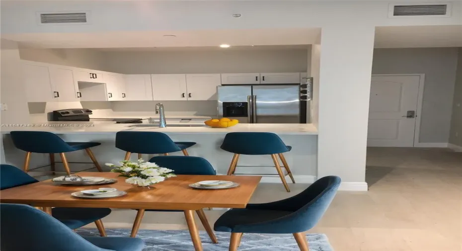 Social area is large enough to fit a dining table and stools facing the kitchen