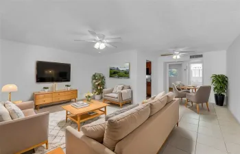 Large and spacious living room with tile flooring and overhead ceiling fans - Staged photo