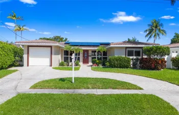 The front of the house, large driveway with an attached garage and additional circular parking, offering plenty of space.

