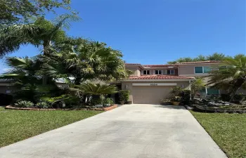 Welcome to this stunning home, featuring a beautifully landscaped front yard with lush tropical foliage and towering palm trees.