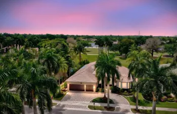 Wide brick paver circular driveway, tall palms, manicured landscaping creates beautiful curb appeal.
