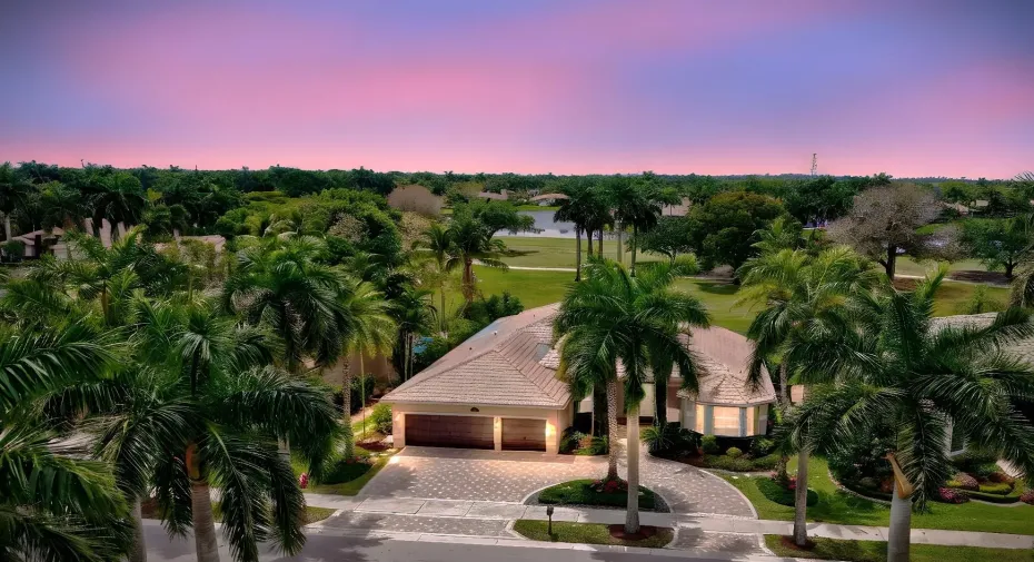 Wide brick paver circular driveway, tall palms, manicured landscaping creates beautiful curb appeal.