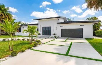 This brand-new modern contemporary home features a flat concrete tile roof, block-paved circular driveway, and impact-resistant windows and doors for lasting beauty and protection.

