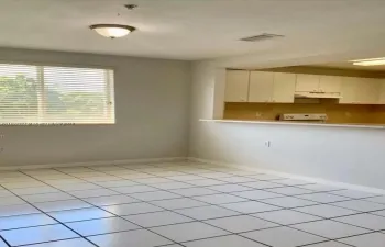spacious living room with large windows and open kitchen with serving counter